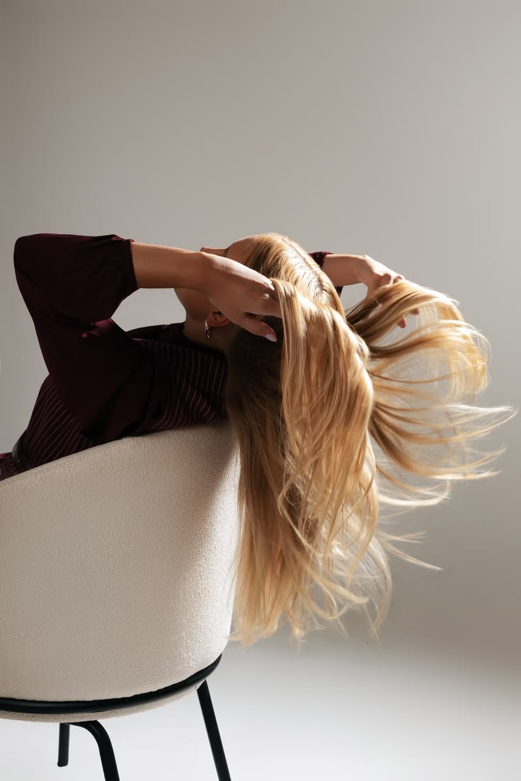 A woman leaning back over a chair, long hair fanned out